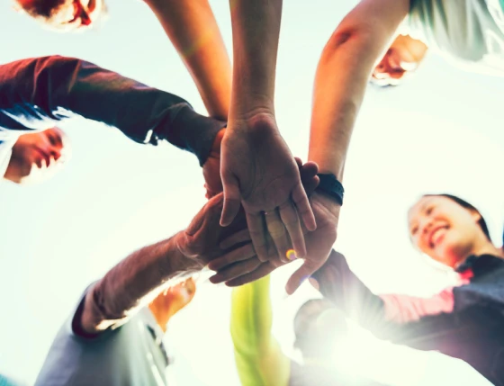 A group of happy friends showing unity putting hand on hand.